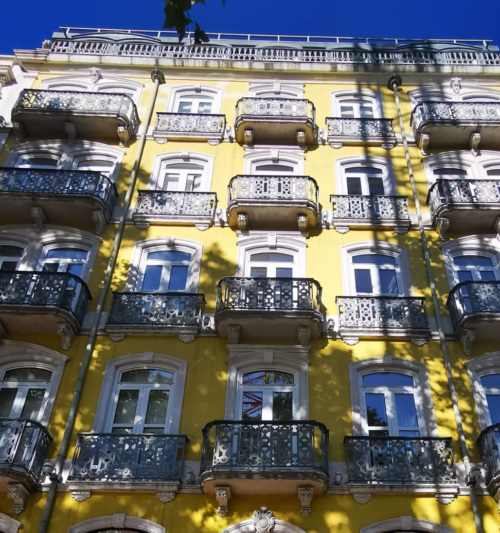 An old building in Portuguese architecture style, with mango-yellow facade and iron balcony.